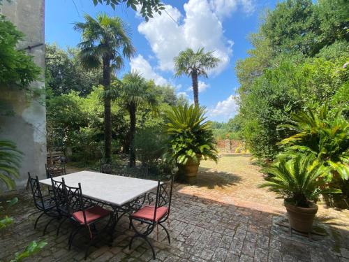 a table and chairs in a garden with palm trees at Usage exclusif - Palazzo du XVI avec piscine in Crespina