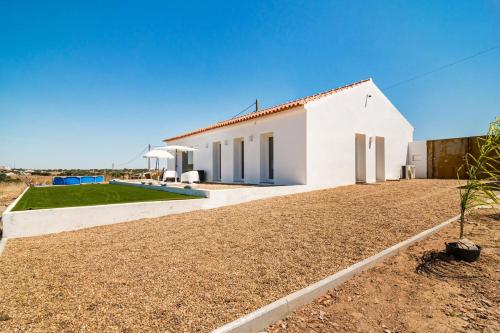 a white house with a gravel driveway at Monte Muro Country House in Mourão