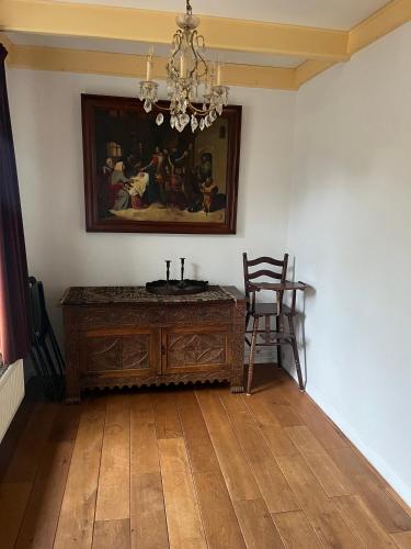a room with a table and a painting and a chair at Hotel Waddengenot in Pieterburen