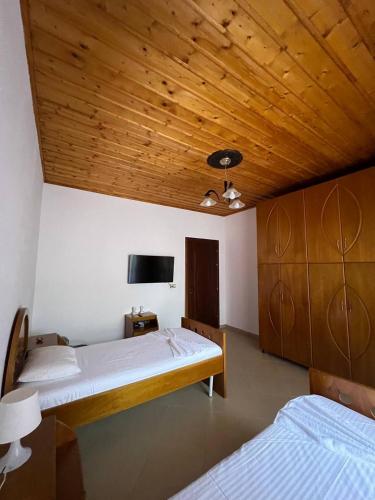 a bedroom with two beds and a flat screen tv at Armando's wooden roof in Berat