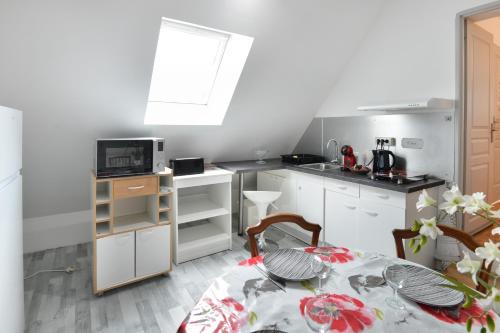 une cuisine avec une table et une cuisine avec un micro-ondes dans l'établissement Pura Vida - Appt à 400m de la plage, à Saint-Aubin-sur-Mer