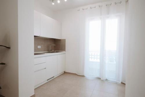 a white kitchen with white cabinets and a window at Gioema in Borgo Vodice