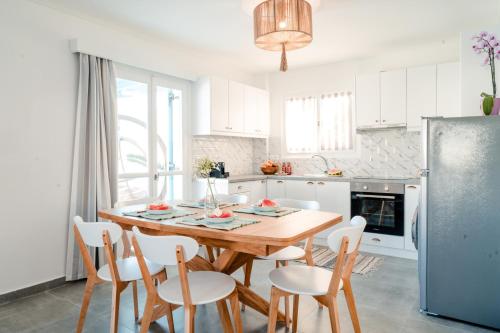 a white kitchen with a wooden table and chairs at Nikis Village in Poros