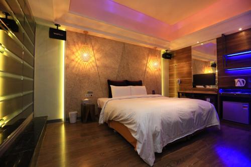 Un dormitorio con una cama blanca y un televisor. en 約客頂級汽車旅館-新竹館, en Hsinchu City