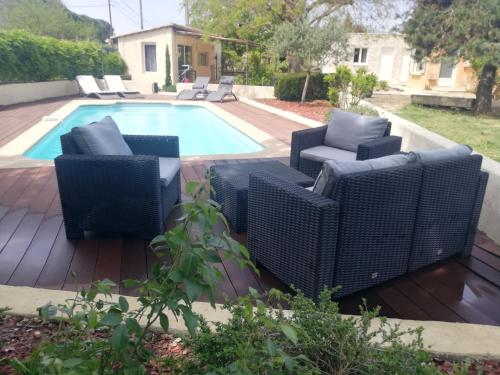 une terrasse avec des chaises en osier et une piscine dans l'établissement Villa Gabriel, à Goult