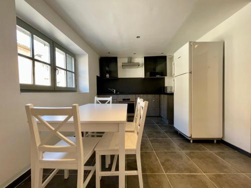 La cuisine est équipée d'une table et de chaises blanches ainsi que d'un réfrigérateur. dans l'établissement Duplex de bezons - parking - Entre centre-ville et cité médiévale, à Carcassonne