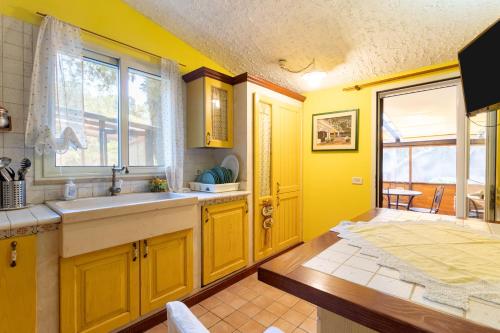 a yellow kitchen with a sink and a window at Villa Lorenz in Putignano