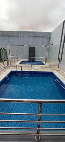 a large swimming pool with blue water and stairs at Nesto Hotel in Manāwirah