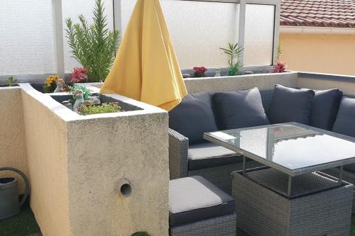 a patio with a table and a yellow umbrella at Duplex apartment with beautiful sea view in Saint-Raphaël
