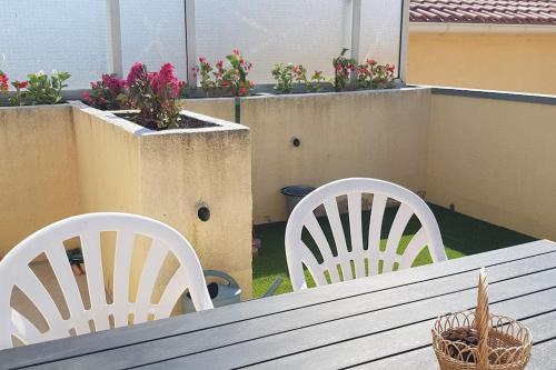 three white chairs sitting around a table on a balcony at Duplex apartment with beautiful sea view in Saint-Raphaël