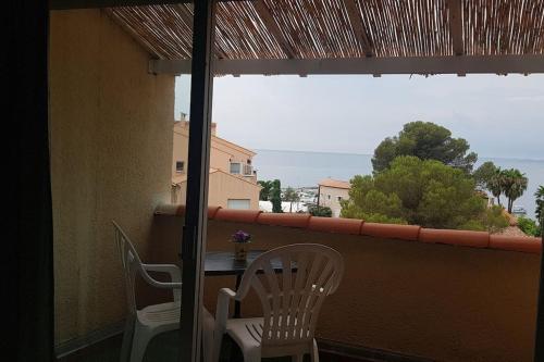 a balcony with a table and chairs and a window at Duplex apartment with beautiful sea view in Saint-Raphaël