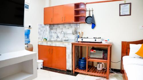 una pequeña cocina con armarios naranjas y fregadero en Studio furnished Apartments Naivasha, en Naivasha