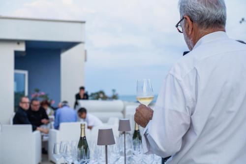 a man holding a glass of white wine at Hotel Mediterraneo in Sottomarina