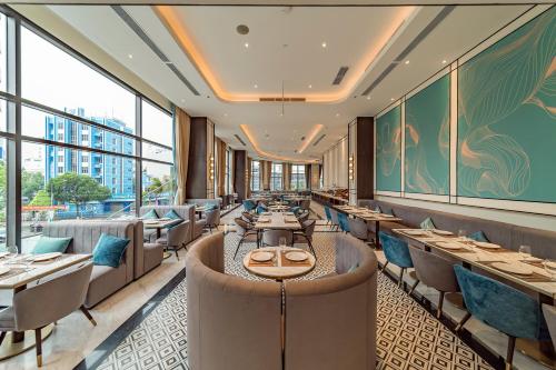 a restaurant with tables and chairs and windows at Charmant Suites a Boutique Hotel Can Tho in Can Tho