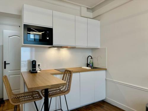 une cuisine avec des armoires blanches et une table en bois dans l'établissement Nouveau studio central Paris, à Paris