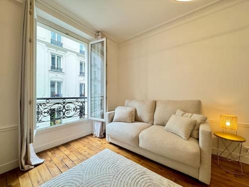 un salon avec un canapé et une grande fenêtre dans l'établissement Nouveau studio central Paris, à Paris