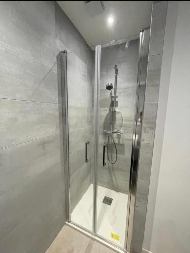 une douche avec une porte vitrée dans une salle de bain dans l'établissement Le Petit Navire, à La Flotte