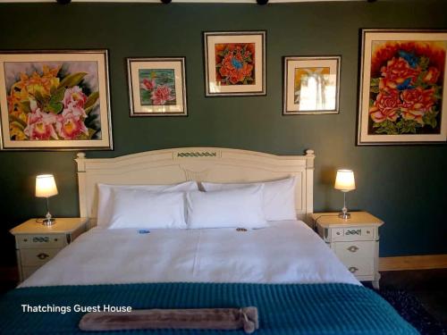 a bedroom with a white bed with two nightstands and two lamps at Thatchings Bed and Breakfast in Nottingham Road