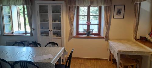 a dining room with a table and chairs and windows at Chalupa u Anenské in Žďárský Potok