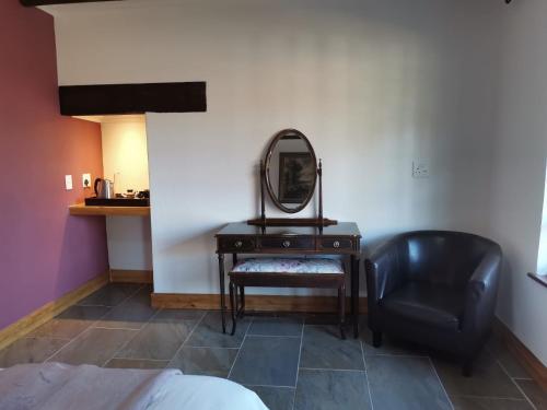 a bedroom with a mirror and a chair and a table at Thatchings Bed and Breakfast in Nottingham Road