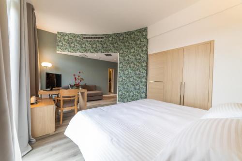 a bedroom with a white bed and a table at Hotel Mioni Royal San in Montegrotto Terme