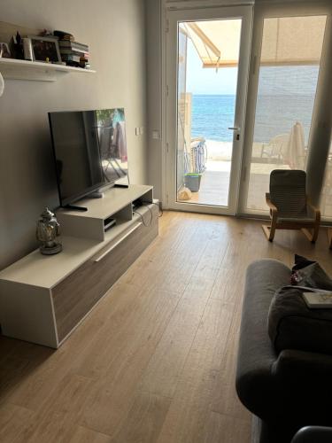 Una sala de estar con un televisor de pantalla plana en un centro de entretenimiento. en Apartamento 1ª línea de playa, en Almería
