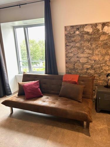 - un canapé brun dans une chambre dotée d'un mur en pierre dans l'établissement Appartement contemporain, à Stiring-Wendel