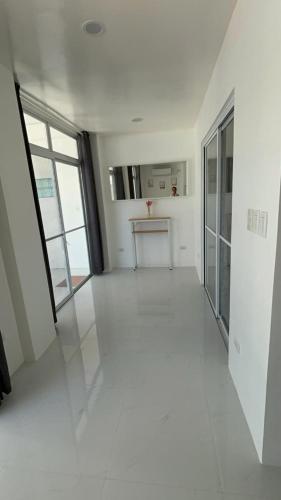 an empty room with white floors and large windows at Pinky's Beach House in Victoria