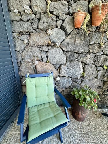 a green chair sitting in front of a stone wall at A Casa do Jaime in Prainha de Baixo