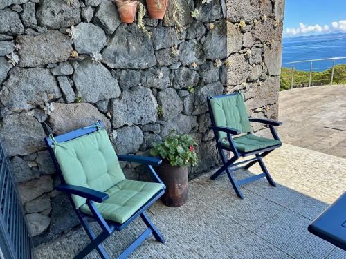 two chairs sitting on a patio next to a stone wall at A Casa do Jaime in Prainha de Baixo