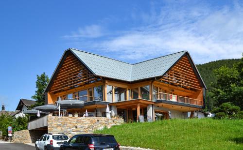 a large wooden house with cars parked in front of it at B&B Hotel Zimmerei mit Frühstück in Lunz am See