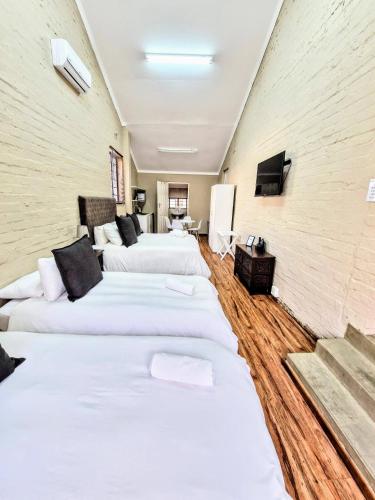 a room with four white beds in it at 9 on Drommedaris in Stellenbosch