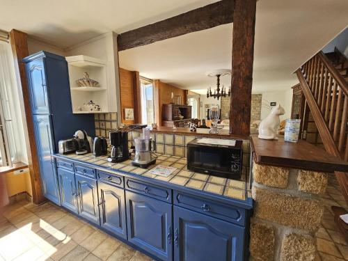 une cuisine avec des placards bleus et un four micro-ondes sur un comptoir dans l'établissement Maison spacieuse avec jardin clos, vélos à disposition, plages à 2 kms, à Tréffiagat