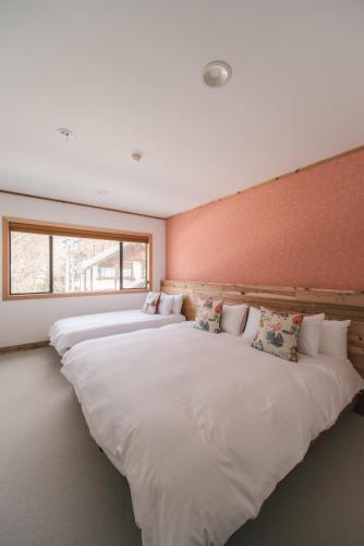 two large white beds in a room with a window at The Brueys Lodge Tangram Madarao in Shinano