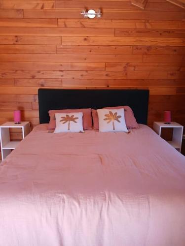 une chambre avec un grand lit avec des draps et des oreillers roses dans l'établissement Gîte jusqu'à 4 personnes, à Prayssas