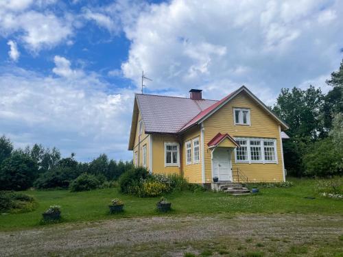 a yellow house on a green field with trees at Pihlajaharju Countryside Escape in Somero