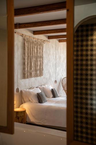 a bedroom with a bed with white sheets and pillows at The Theodore Boutique Hotel- adults only 16 plus in Agia Marina Nea Kydonias