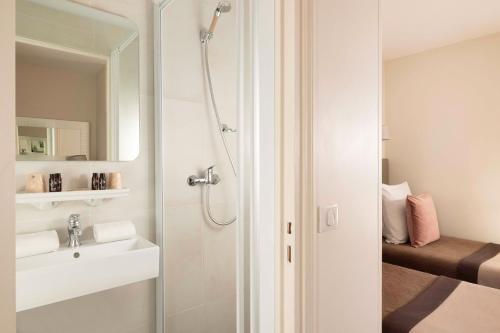 a bathroom with a shower and a sink and a mirror at H&ocirc;tel Saint Pierre in Paris