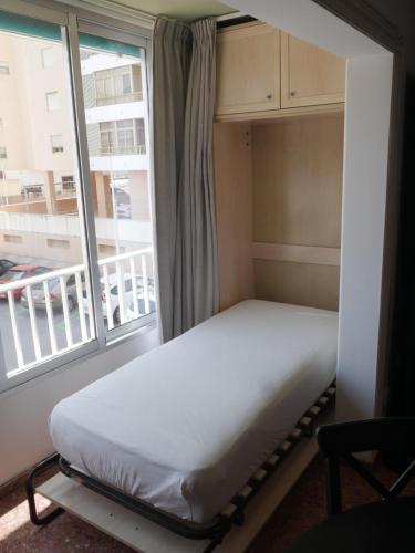 a bed in a room with a large window at Malvarrosa, 1-6 in Cullera