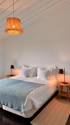 a bedroom with a large white bed and two tables at Casas da Prainha D in Canto da Areia