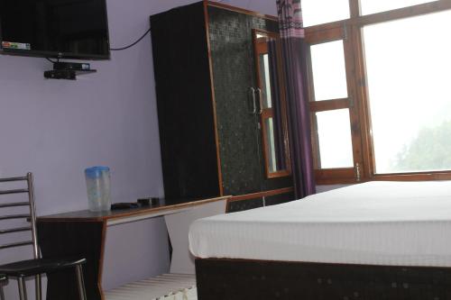 a bedroom with a bed and a desk and a television at THE GROOVE GARDEN DHANOLTi in Dhanaulti
