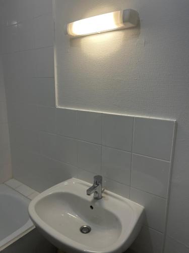 La salle de bains est pourvue d'un lavabo et d'une lumière sur le mur. dans l'établissement Le coins sympa, à Lyon