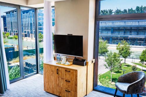 a room with a tv and a chair and large windows at River Inn Hotel in Yakkasaray