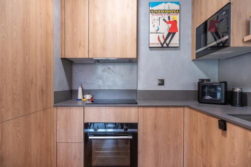 a kitchen with wooden cabinets and a stove at ISARD & SPA by SELECT RENTALS in El Tarter