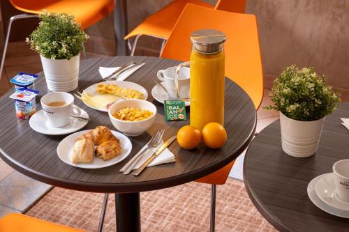 a black table with breakfast food and a bottle of orange juice at Hôtel Saint Pierre in Paris
