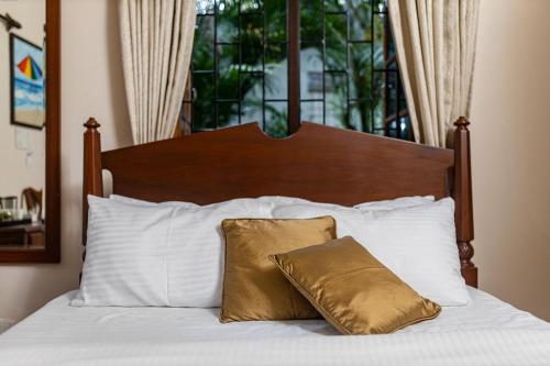 a bed with white pillows and a brown pillow at Mistral Holidays Near Trinity Beach & Benaulim Beach in Benaulim
