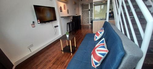 a living room with a blue couch and a television at SY Staycation - Studio in Bayan Lepas