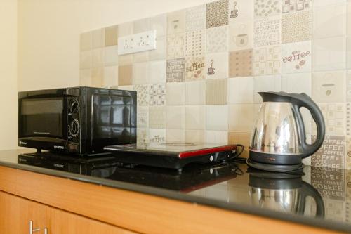 a microwave and a tea kettle on a kitchen counter at Mistral Holidays Near Trinity Beach & Benaulim Beach in Benaulim