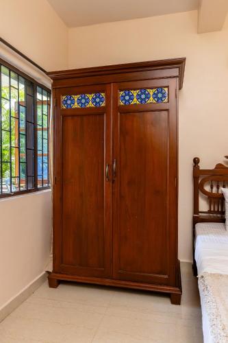 a wooden door in a room with a bed at Mistral Holidays Near Trinity Beach & Benaulim Beach in Benaulim