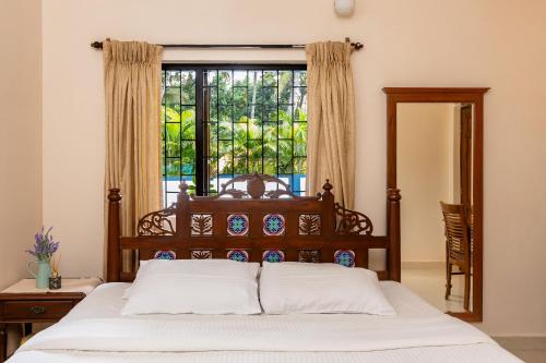 a bedroom with a bed and a large window at Mistral Holidays Near Trinity Beach & Benaulim Beach in Benaulim